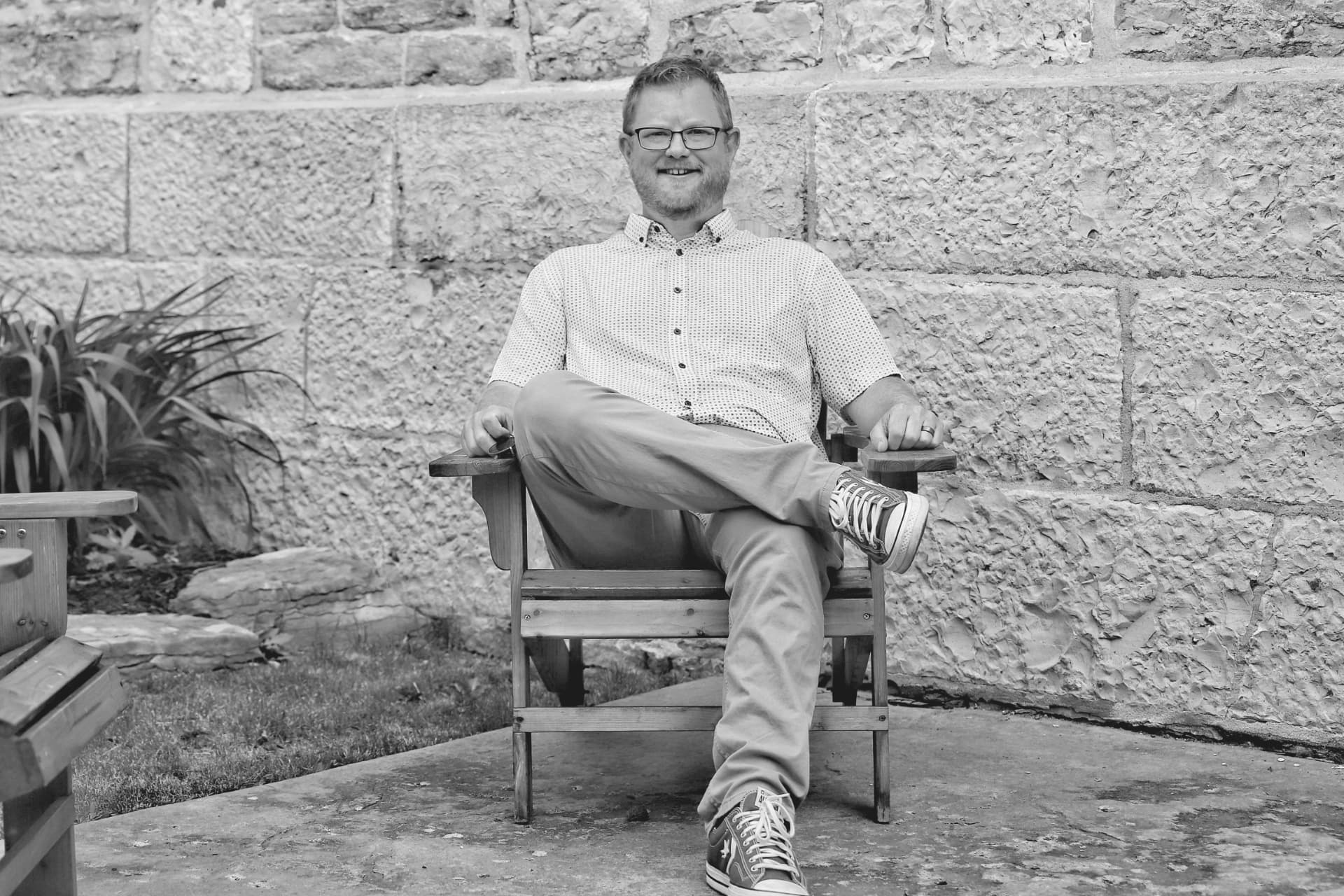 Brad Way, founder of Inside Out, seated outdoors against a stone wall